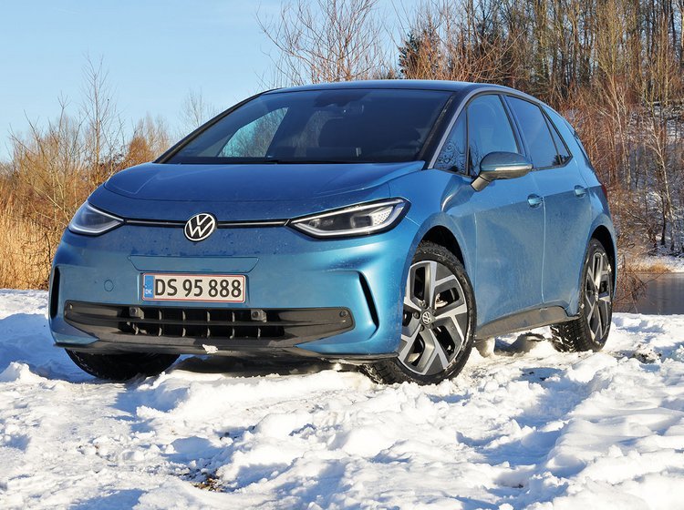 En blå VW ID.3 holder i sne med en skovsø i baggrunden