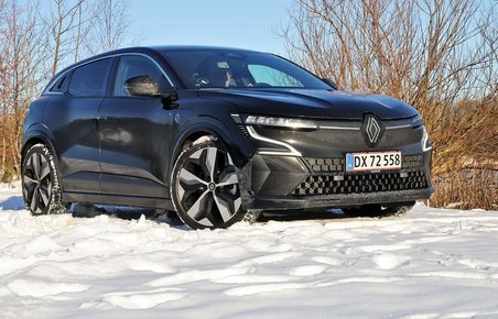 En sort Renault Megane holder i sne med buske i baggrunden