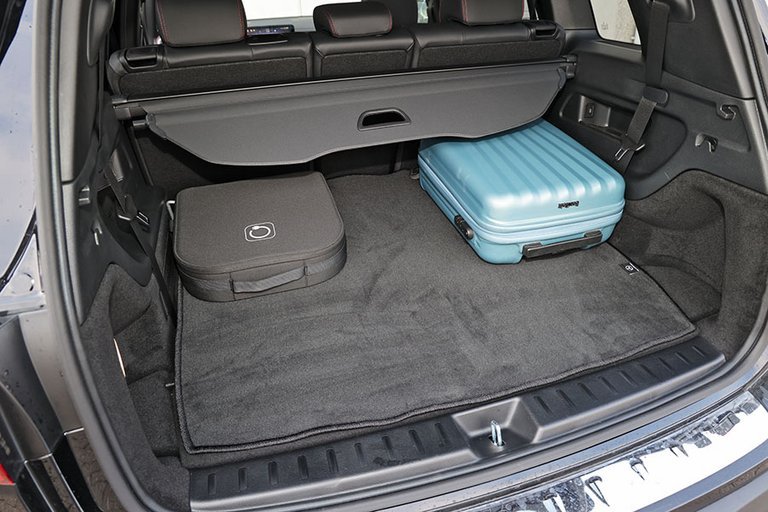 Bagagerum i en Mercedes RQB med blå kuffert og ladekabler