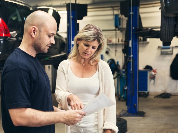 Kvinde taler med mekaniker på et værksted.