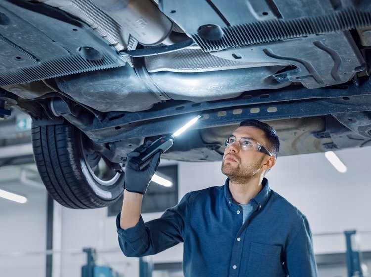 Kontrol af rust på en bil, der er kørt op på en lift.