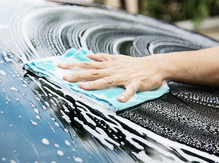 Fokus på hånd og klud, der vasker forruden på en bil. 