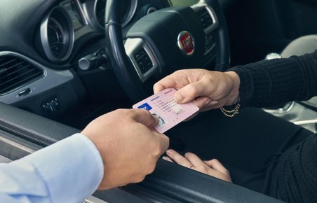 Kørekort rækkes ud af bilvindue.