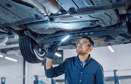 Kontrol af rust på en bil, der er kørt op på en lift.