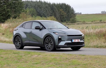 Toyota C-HR+ kører på landevej med træer og marker i baggrunden