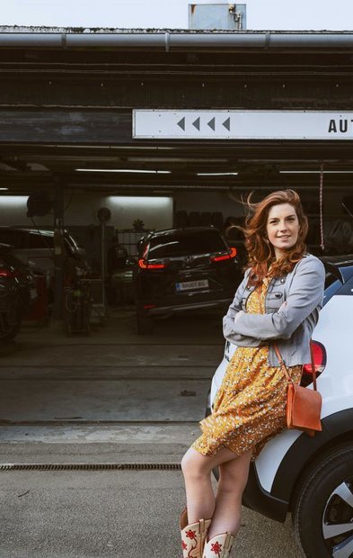 Bilreparation – kvinde på værksted med sin brugte bil