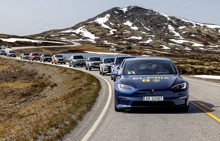 Tesla Model S kører i fjellet i Norge med en lang række elbiler bag sig. 